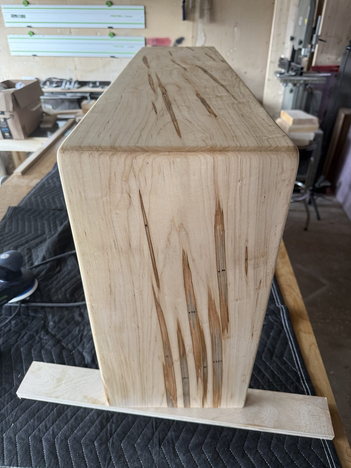 Waterfall corner of the wormy maple tray table seen from the end, with worm tracks across the grain
